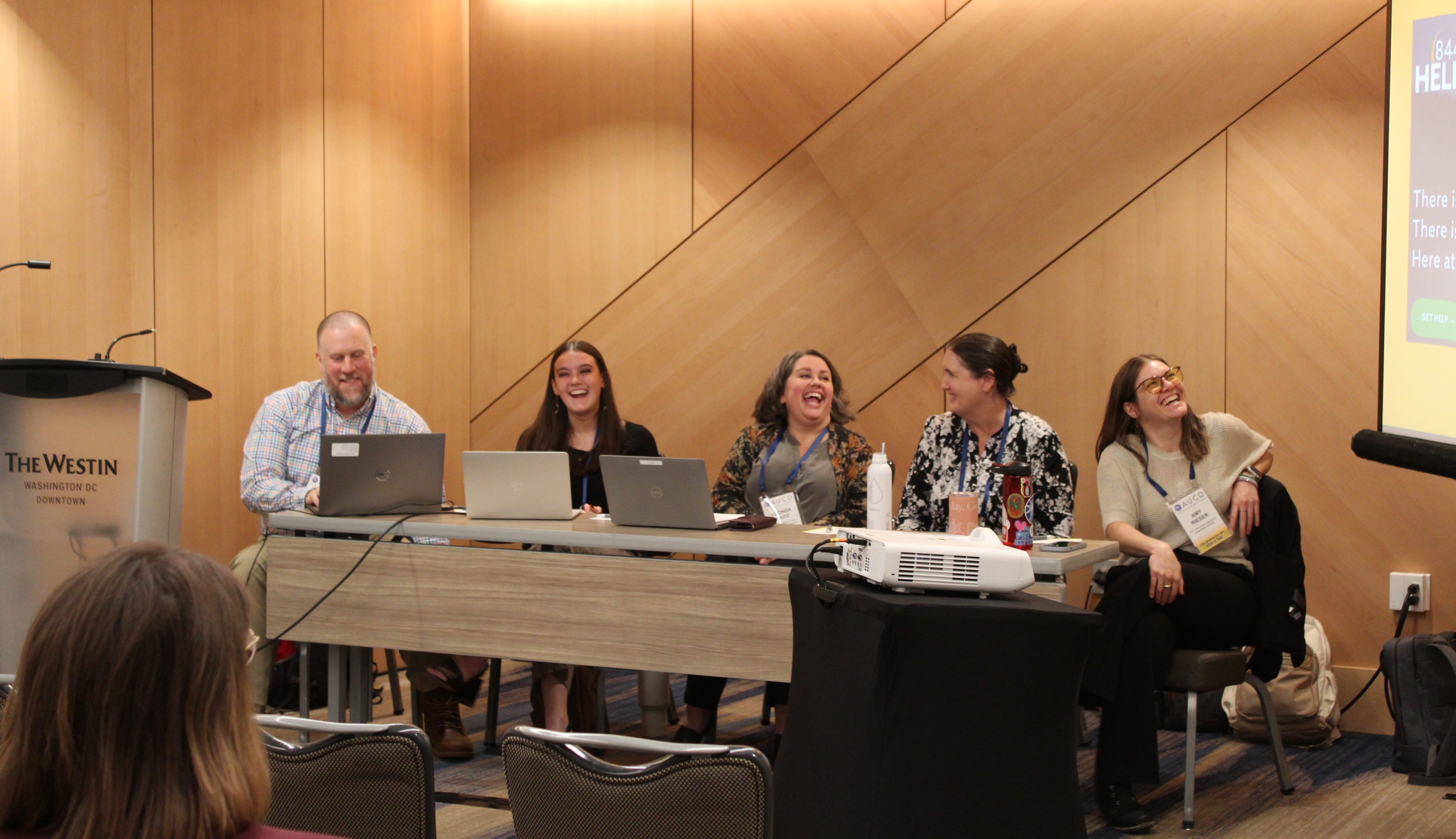 A group of Conference presenters laugh as they discuss their concurrent.