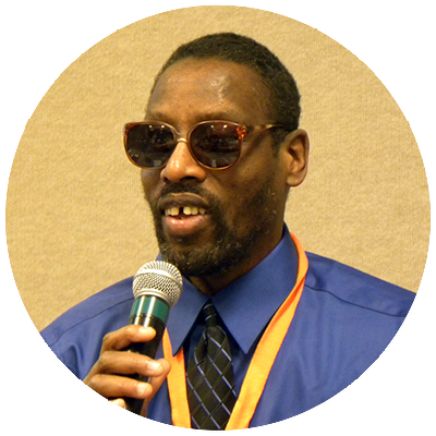 Chester Finn, a black man with wearing sunglasses and speaking into a microphone.