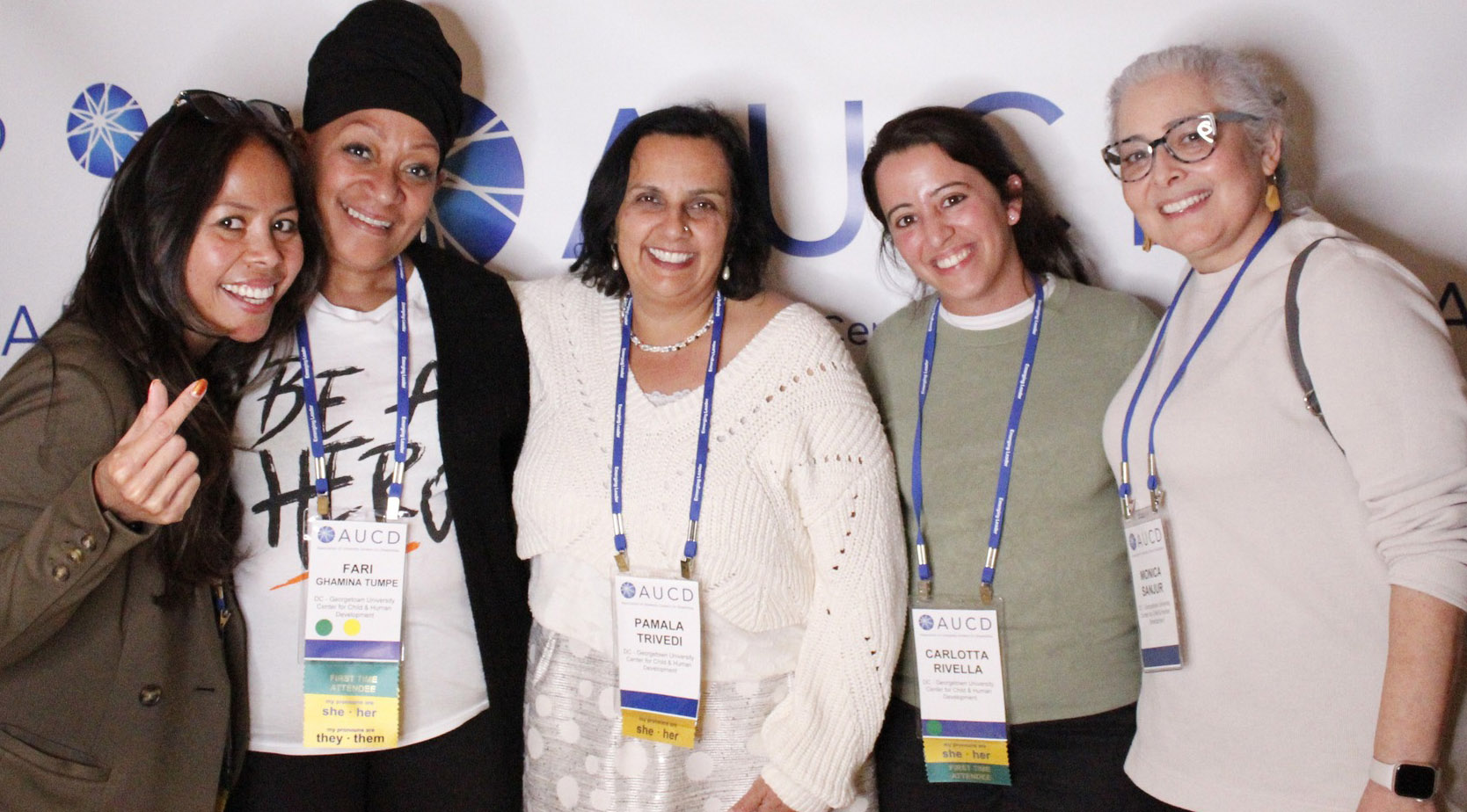 Five conference attendees standing arm in arm in front of bannner that says AUCD.