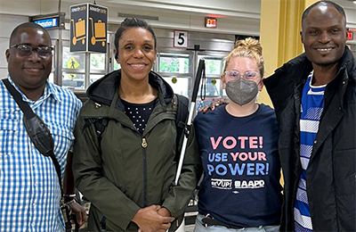 A group of four people (left to right): an African man, an African American woman, a white American woman, and an African man posing for a group photo at the airport, smiling into the camera. Text on the image reads: Spring 2025 Professional Fellow Hosting Opportunities! Apply by January 31, 2025 http://pfpinclusion.org/hosting/