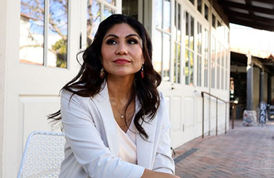 Azucena Bravo, a Mexican woman with long brown hair wearing a blazer and blouse. 