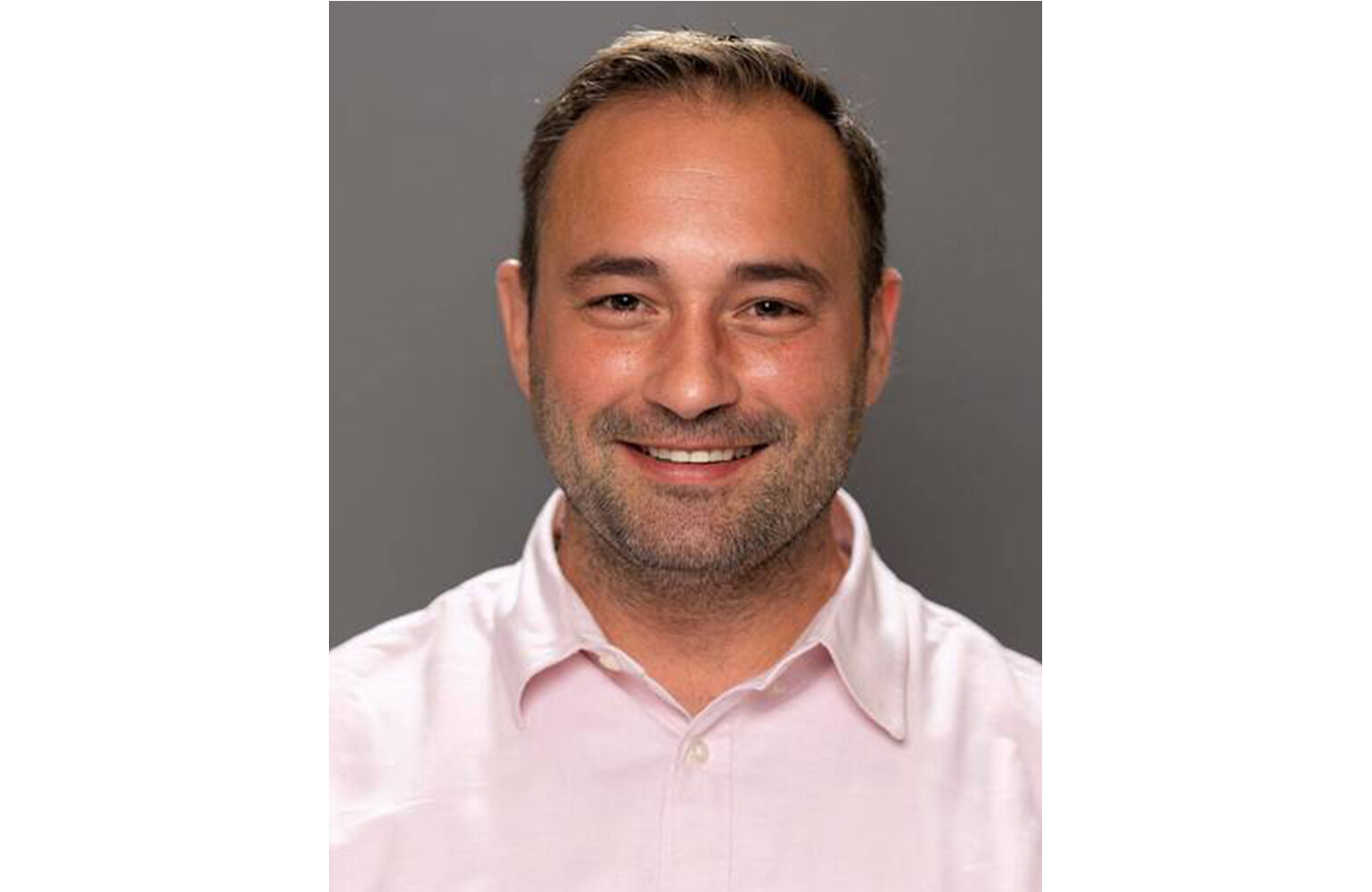 Headshot of Dr. Joseph Lambert, a white man, mid- to late thirties of medium build. Lambert smiles with brown eyes, light brown hair, and beard stubble, wearing a light pink button-down shirt.