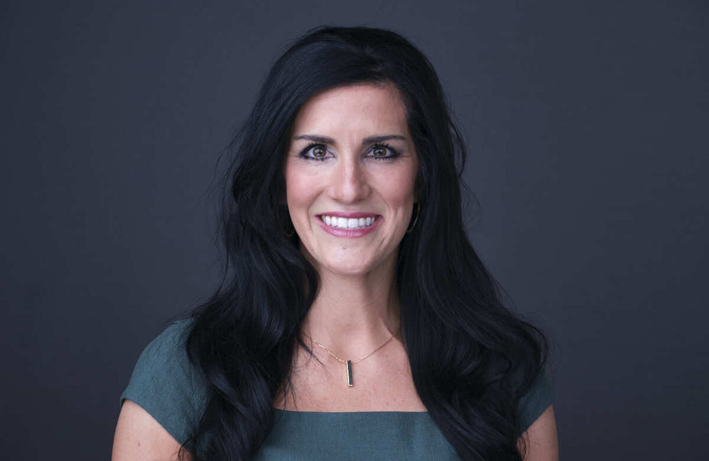 Image of a white woman with longbrown hair wearing a blue blouse.