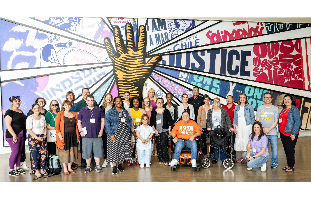 AUCD Leadership Academy particpants standing and sitting in front of a Civil Rights Mural.