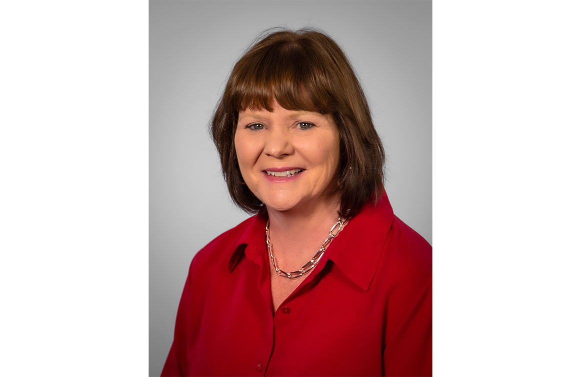 Robin Miller, A white woman with shoulder length hair wearing a red blouse. 