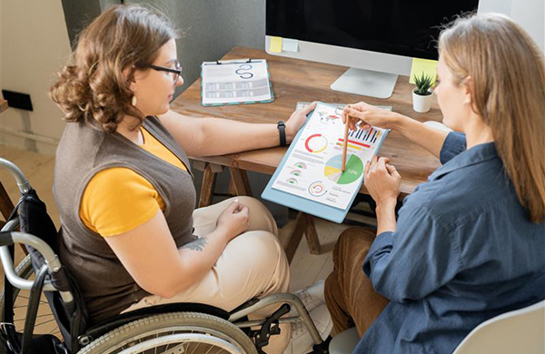 Two youngbusinesswomen discussing financial charts and diagrams while one of them pointingat data and explaining it. 