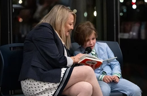 Image of Pamela High reading a book with a young boy. 